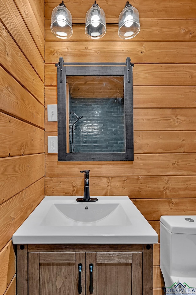 bathroom with toilet, vanity, and wood walls