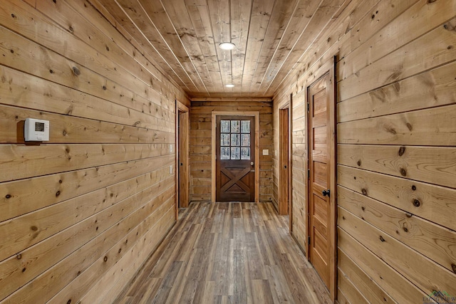 doorway with hardwood / wood-style flooring, wooden ceiling, and wooden walls