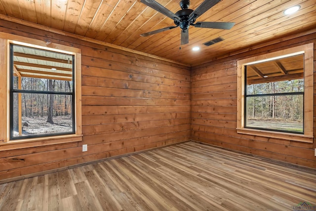 empty room featuring wooden ceiling, wood-type flooring, wood walls, and ceiling fan