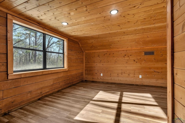 additional living space featuring light wood-type flooring, vaulted ceiling, wood walls, and wooden ceiling