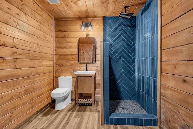 bathroom with toilet, a tile shower, wood walls, and wood ceiling