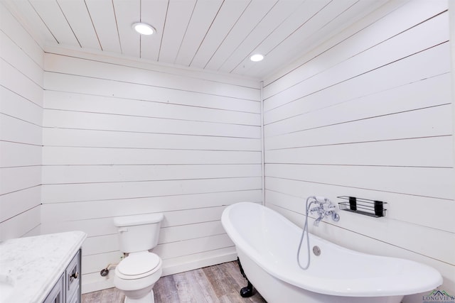 bathroom featuring wooden walls, a washtub, vanity, and hardwood / wood-style flooring