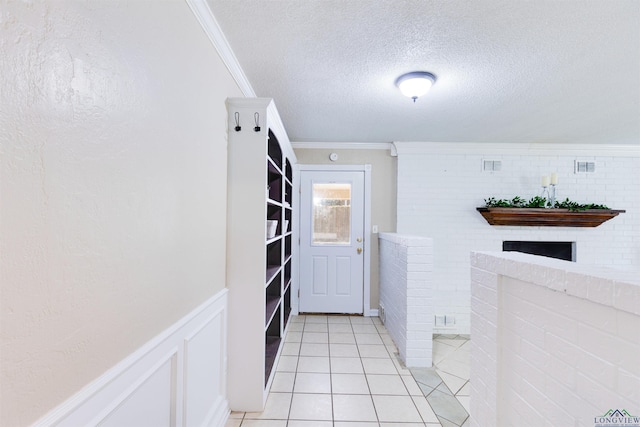 laundry area featuring crown molding, light tile patterned floors, and a textured ceiling