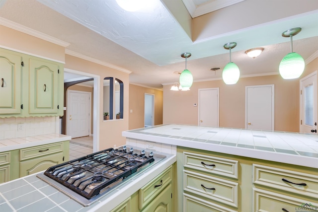 kitchen with tile countertops, stainless steel gas stovetop, backsplash, and hanging light fixtures