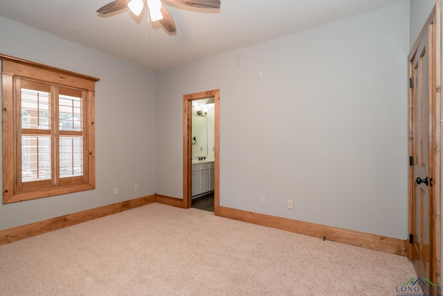 unfurnished bedroom with ensuite bathroom, ceiling fan, light colored carpet, and sink