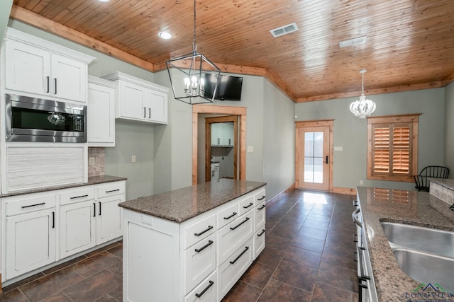 kitchen featuring white cabinets, decorative light fixtures, stainless steel microwave, and wood ceiling