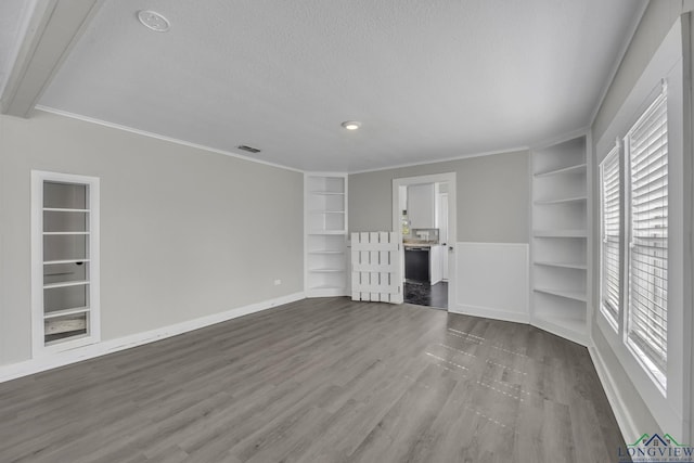 3608 Fm 1970, Carthage, TX 75633 - unfurnished living room featuring built in features, plenty of natural light, a textured ceiling, wood finished floors, and ornamental molding
