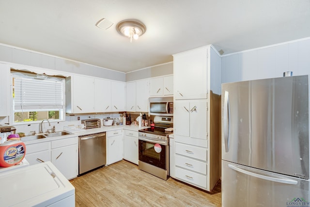 1504 Alice St, Gladewater, TX 75647 - kitchen featuring appliances with stainless steel finishes, washer / clothes dryer, light wood-style flooring, light countertops, and white cabinets