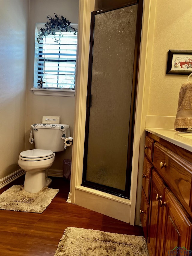 bathroom featuring hardwood / wood-style floors, vanity, a shower with shower door, and toilet