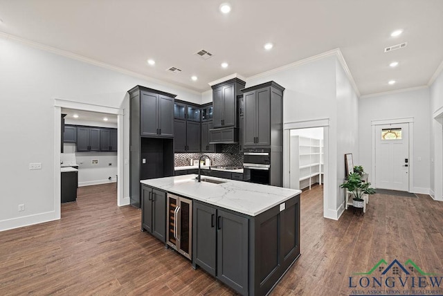 kitchen featuring a center island with sink, wine cooler, dark hardwood / wood-style floors, and light stone counters