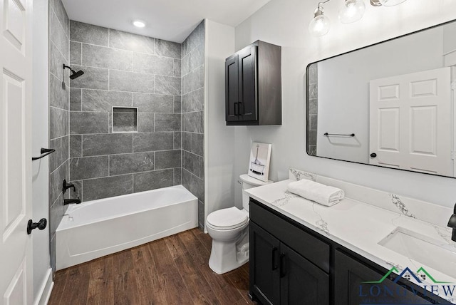 full bathroom featuring hardwood / wood-style floors, vanity, toilet, and tiled shower / bath