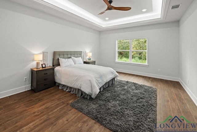 bedroom featuring a tray ceiling, ceiling fan, and dark wood-type flooring