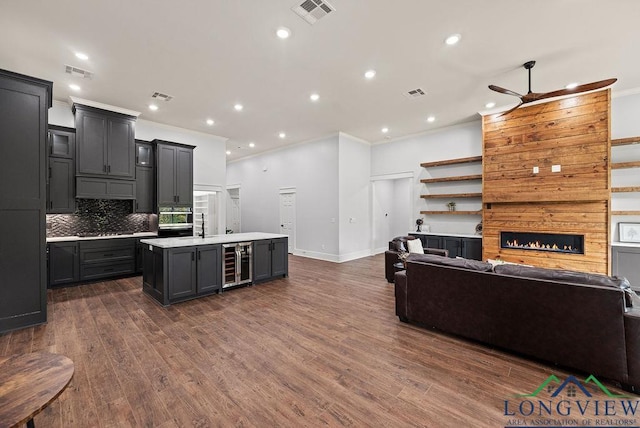 kitchen featuring crown molding, wine cooler, ceiling fan, dark hardwood / wood-style floors, and an island with sink