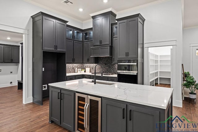 kitchen with dark hardwood / wood-style flooring, light stone counters, beverage cooler, crown molding, and sink