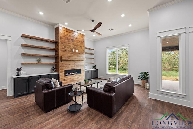 living room with ceiling fan, a fireplace, ornamental molding, and dark wood-type flooring