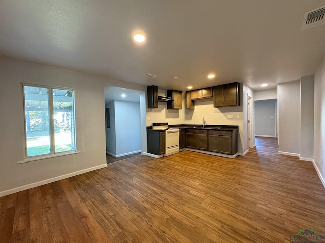 kitchen featuring dark brown cabinetry, wall chimney range hood, hardwood / wood-style floors, and white range with electric stovetop