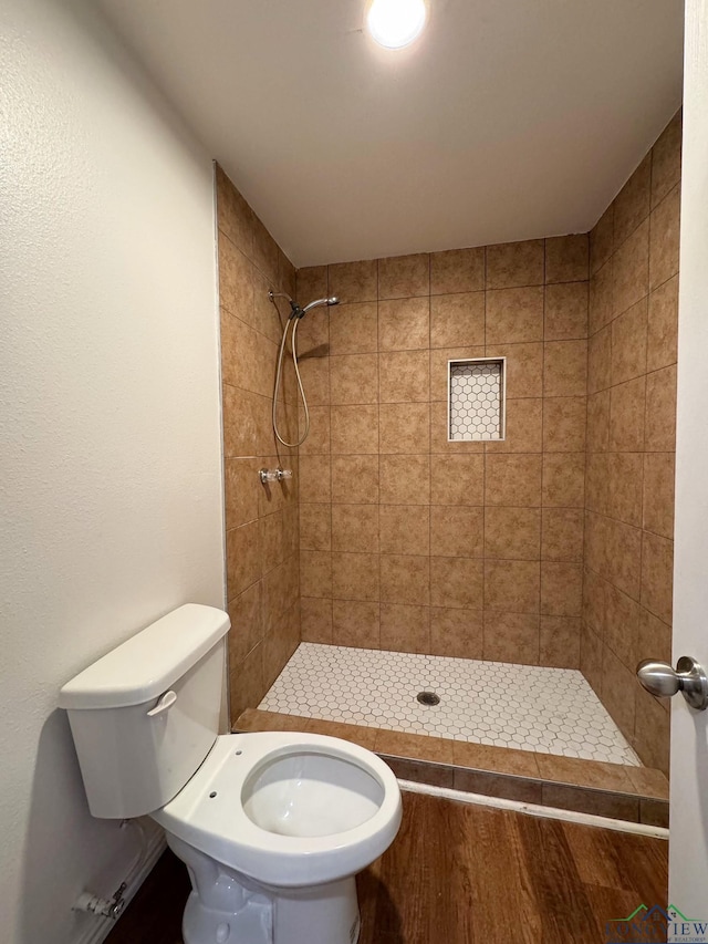 bathroom with tiled shower and toilet