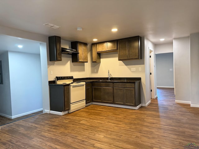 kitchen featuring electric stove, sink, wall chimney range hood, dark brown cabinets, and dark hardwood / wood-style flooring