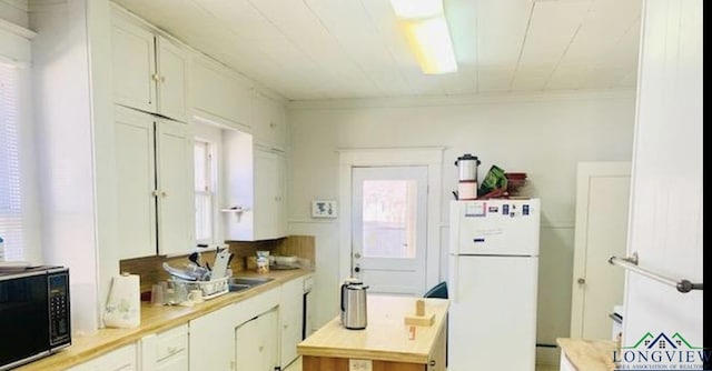 kitchen with white cabinets, white refrigerator, and crown molding