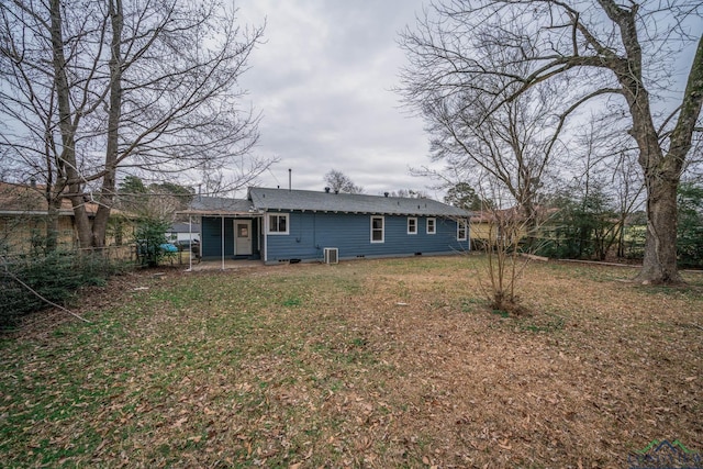 rear view of property featuring central AC, fence, and a lawn