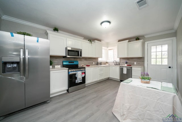 kitchen with visible vents, white cabinets, appliances with stainless steel finishes, light countertops, and crown molding