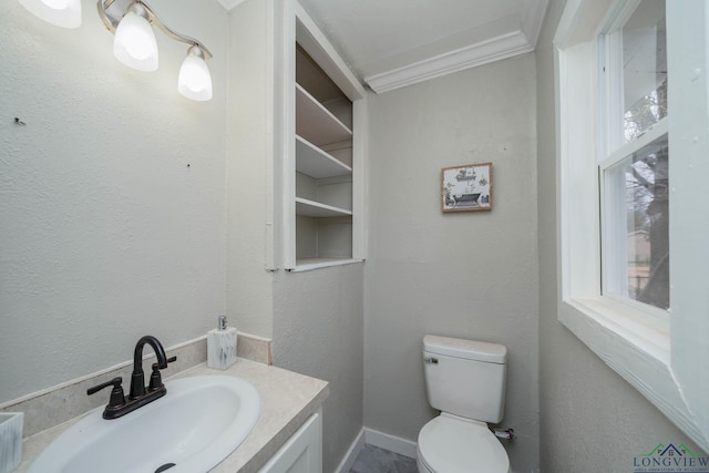 bathroom featuring a textured wall, vanity, toilet, and crown molding