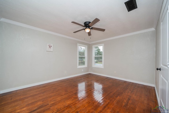 spare room with crown molding, wood finished floors, visible vents, and baseboards