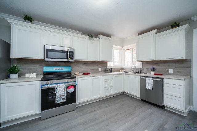 kitchen featuring stainless steel appliances, backsplash, light countertops, and white cabinetry