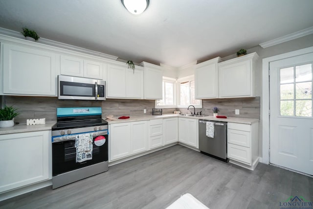 kitchen featuring a sink, white cabinets, light countertops, appliances with stainless steel finishes, and tasteful backsplash