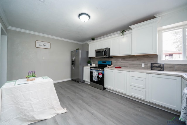 kitchen featuring appliances with stainless steel finishes, light countertops, white cabinetry, and ornamental molding