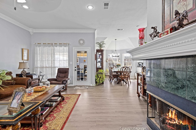 living room with ornamental molding, an inviting chandelier, and light hardwood / wood-style flooring