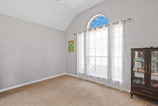 carpeted spare room featuring vaulted ceiling