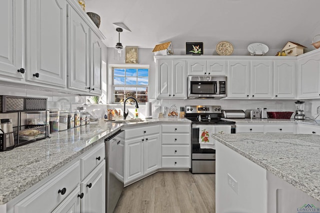 kitchen with white cabinetry, sink, decorative backsplash, hanging light fixtures, and stainless steel appliances