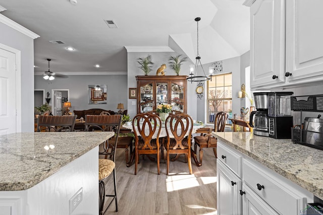 kitchen featuring white cabinetry, hanging light fixtures, crown molding, and light hardwood / wood-style flooring