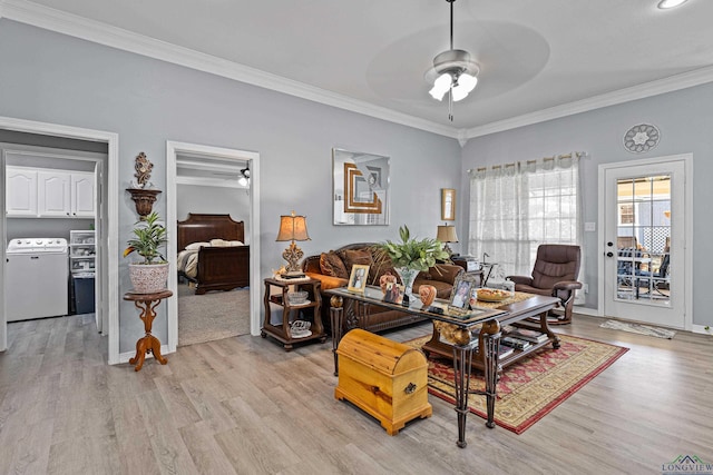 living room featuring ornamental molding, washer / dryer, and light hardwood / wood-style flooring