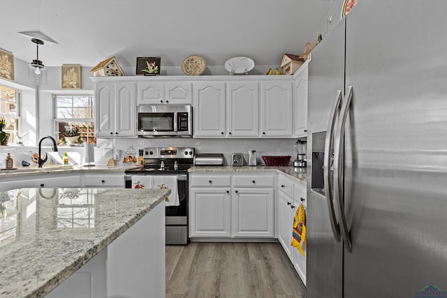 kitchen with hanging light fixtures, white cabinets, and appliances with stainless steel finishes