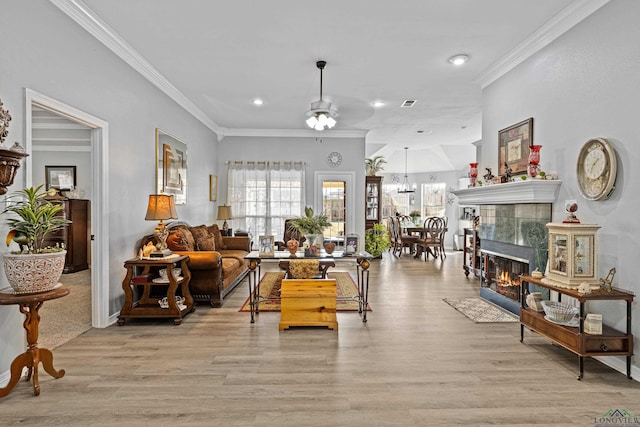 living room featuring a tiled fireplace, crown molding, and light hardwood / wood-style flooring