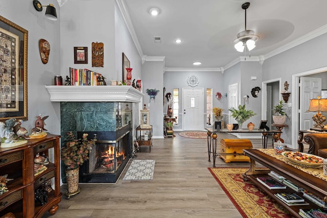 sitting room with crown molding, ceiling fan, wood-type flooring, and a fireplace