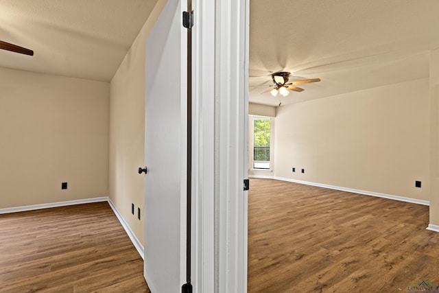 spare room with a textured ceiling, baseboards, a ceiling fan, and dark wood finished floors