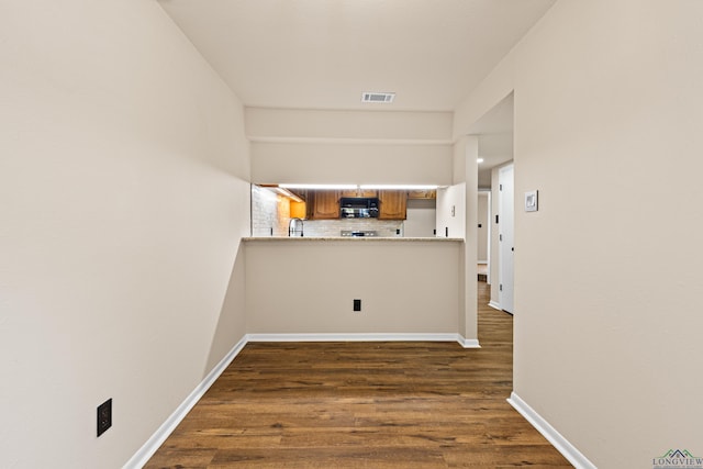 hall featuring dark wood-style flooring, baseboards, and visible vents