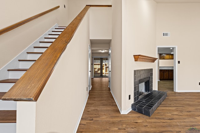 interior space with visible vents, baseboards, a high ceiling, stairway, and wood finished floors