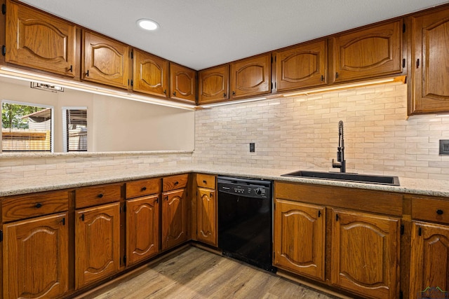 kitchen featuring a sink, light wood-type flooring, dishwasher, and brown cabinets