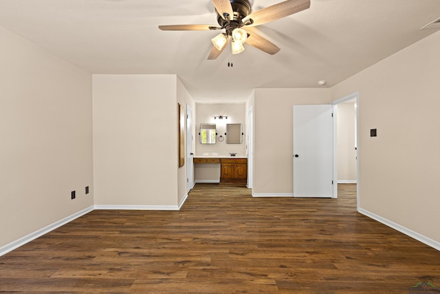 unfurnished bedroom featuring baseboards, electric panel, ensuite bath, a ceiling fan, and dark wood finished floors