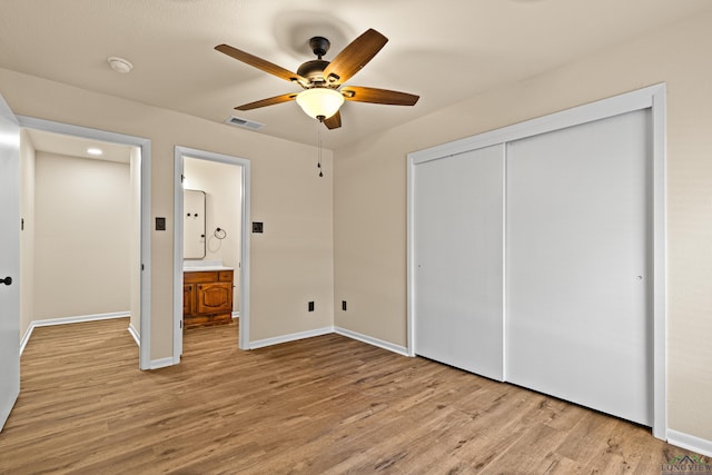 unfurnished bedroom with baseboards, wood finished floors, a closet, and visible vents