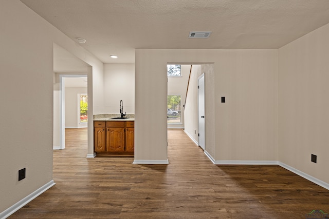 interior space with dark wood-type flooring, a textured ceiling, visible vents, a sink, and baseboards