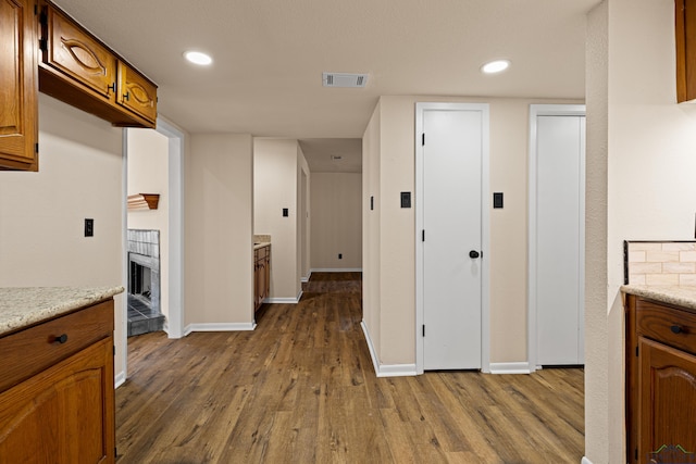 kitchen with a fireplace, visible vents, brown cabinets, and dark wood-style floors