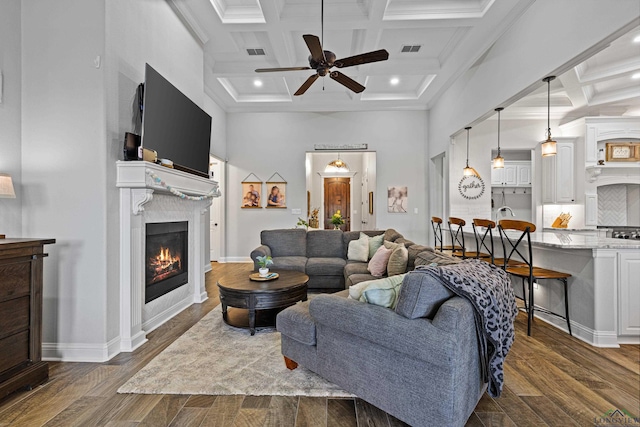 living room featuring dark hardwood / wood-style flooring, ceiling fan, ornamental molding, and a towering ceiling