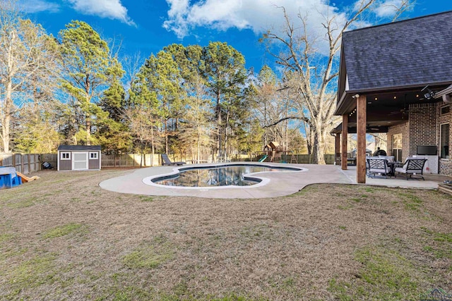 view of yard with a patio area, a fenced in pool, a storage unit, and a playground