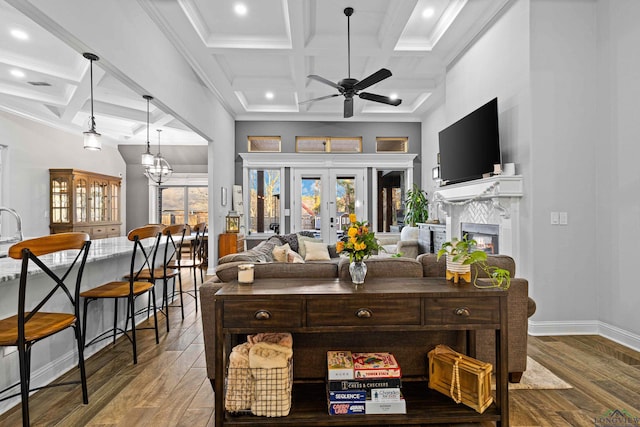 living room featuring coffered ceiling, french doors, wood-type flooring, and a towering ceiling