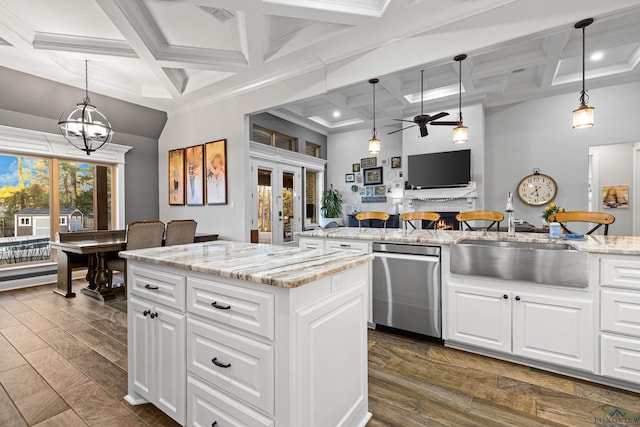 kitchen featuring white cabinets, stainless steel dishwasher, decorative light fixtures, a kitchen island, and sink